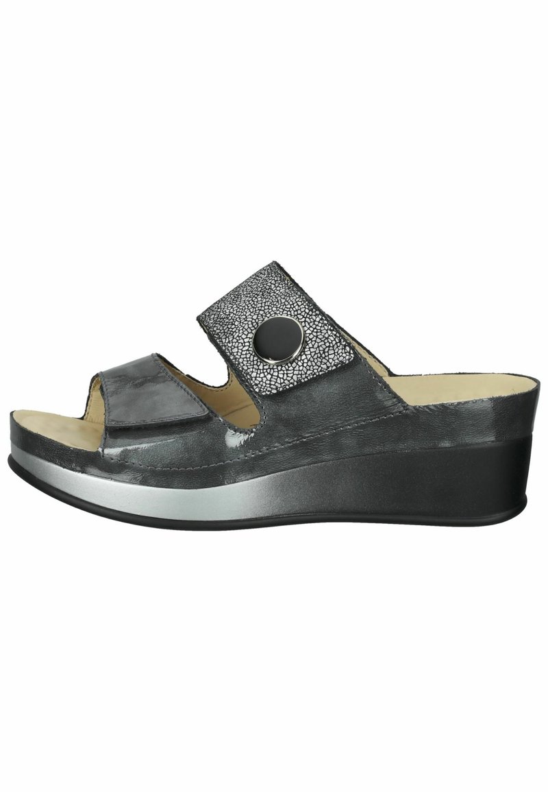 Black slip-on wedge sandal with an open toe, featuring a textured strap with a circular accent and a smooth, shiny finish.