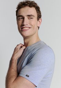 Grijs-blauw T-shirt met korte mouwen en een gestructureerde afwerking, met een klein zwart logo-detail op de linkermouw, met een ontspannen pasvorm.
