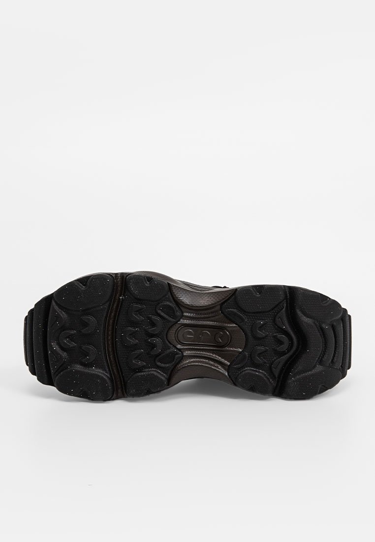 Semelle de chaussure de sport noire avec une surface en caoutchouc texturé, présentant un motif ondulé et des éléments de traction surélevés pour une adhérence et une stabilité améliorées.