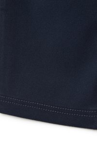 Tissu bleu marine avec une texture lisse. Présente un ourlet soigneusement cousu avec un fil contrastant. Le matériau semble durable et flexible.