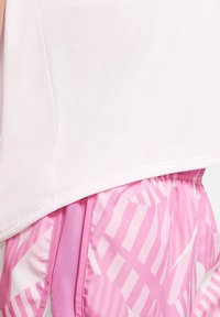 White athletic top with short sleeves paired with pink shorts featuring a geometric pattern. The shorts have an elastic waistband and mesh detail.