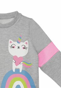Grå sweatshirt med et farverigt enhorn-kat grafik, der har et pink hjerte og regnbue design. Pink detaljer på ærmerne forstærker det visuelle udtryk.