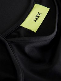 Îmbrăcăminte sport din țesătură neagră cu o textură netedă. Dispune de o etichetă neon galben contrastantă cu "JYXX" imprimat în negru. Captura de aproape evidențiază cusăturile.