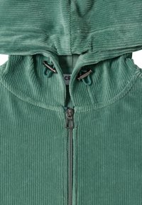 Doudoune zippée en velours côtelé vert avec un col haut, des cordons de serrage réglables et une surface texturée en ribbée. Fermeture éclair à l'avant.