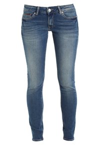Jeans ajustados azules de mezclilla con una cintura de altura media, diseño estándar de cinco bolsillos y un ligero desgastado en toda la tela.