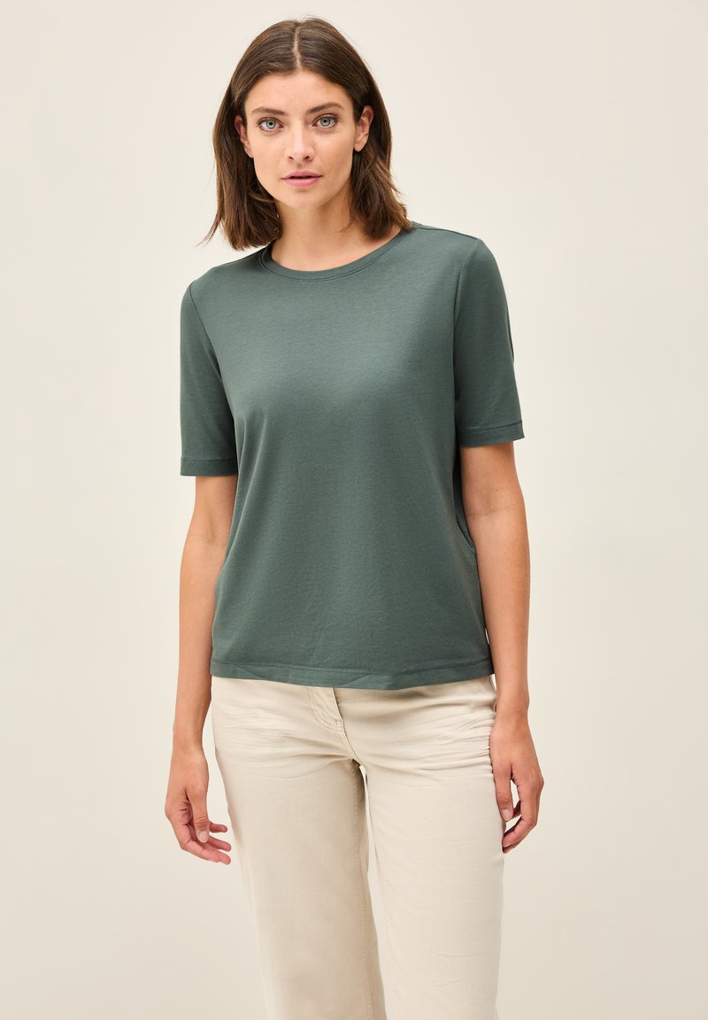 Mørkegrøn t-shirt med korte ærmer i blødt stof og rund halsudskæring. Designet med en afslappet pasform og diskrete slides i siderne for komfort.