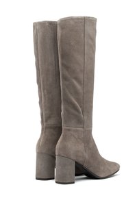 Wysokie damskie botki zamszowe w stonowanym kolorze taupe, z masywnymi obcasami i szpiczastymi noskami, ułożone obok siebie na białym tle.