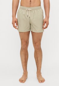 Ανοιχτό μπεζ μαγιό με ελαστική μέση, κλείσιμο με κορδόνι και πλαϊνές τσέπες, κατασκευασμένο από λείο, γρήγορα στεγνώνων ύφασμα.