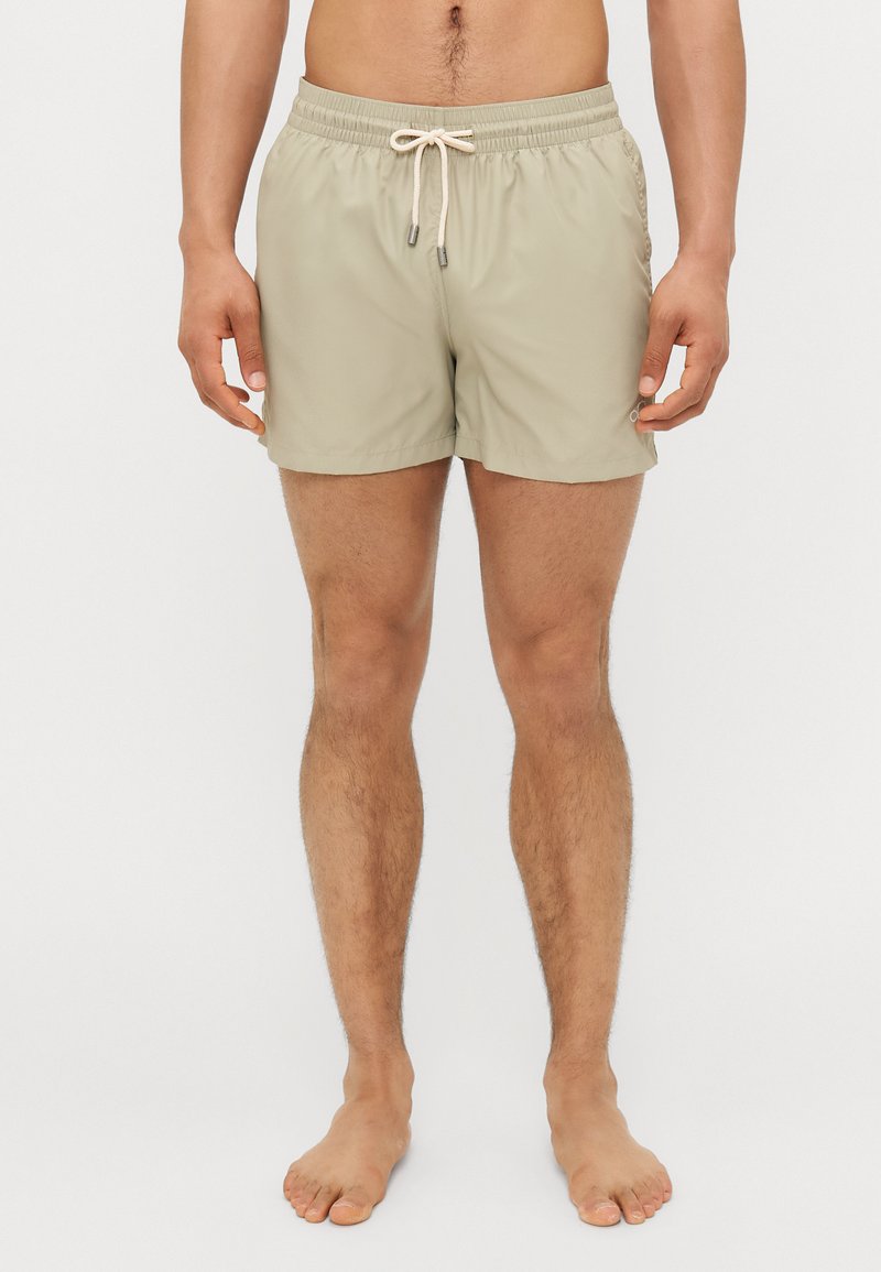 Ανοιχτό μπεζ μαγιό με ελαστική μέση, κλείσιμο με κορδόνι και πλαϊνές τσέπες, κατασκευασμένο από λείο, γρήγορα στεγνώνων ύφασμα.