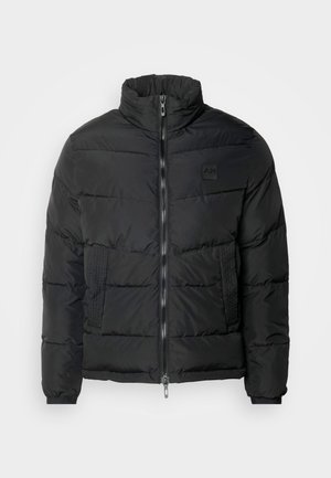 Zwarte pufferjack met een hoge kraag, ritssluiting, gequilt textuur en een logo-opdruk op de borst. Voorzien van elastische manchetten en zijzakken.