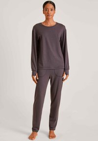 Grijze lange mouwen top en bijpassende broek, gemaakt van zacht stof. De top heeft een ronde hals; de broek heeft opvallende zijzakken met stiksel detail.