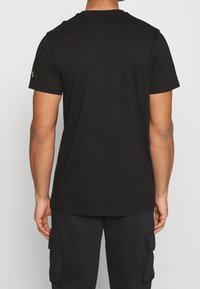 Svart bomull T-shirt med rund halsringning och korta ärmar, med en liten logotyp på vänster ärm. Slät textur, avslappnad passform.