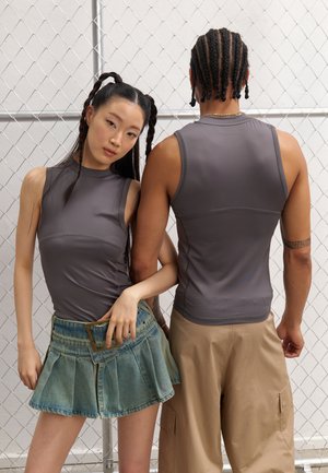 Graue, figurbetonte ärmellose Tops aus dehnbarem Material, kombiniert mit einem Jeansrock mit Falten und einer khakifarbenen Cargo-Hose.