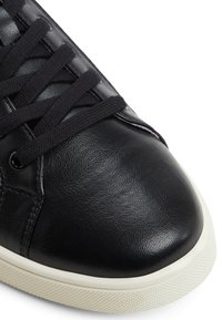 Svart lädersneaker med en slät textur, rundad tå, svarta snören och en vit gummisula med ett texturerat greppmönster.