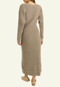 Ribbed Strickmaxikleid in Taupe, mit langen Ärmeln und taillierter Passform. Weiche Textur mit fließender Silhouette und knielang.