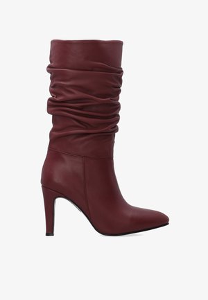 Kobiece burgundowe skórzane botki do połowy łydki w stylu luźnym, z ostro zakończonym noskiem i wysokim, smukłym obcasem, zaprezentowane w profilu na białym tle.