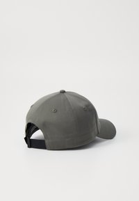 Grå bomull baseballcap med buet skygge, seks-panel struktur og justerbar stropp bak. Strukturert stoff og ventilasjonslufthull.