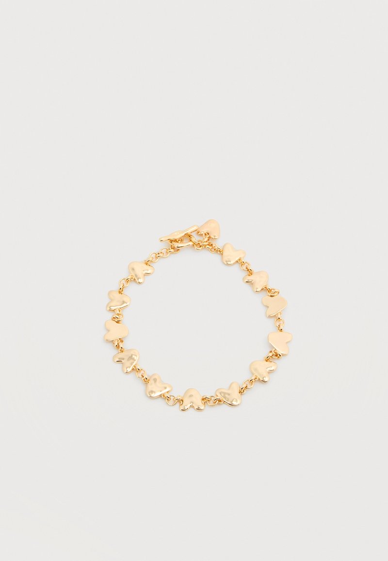 Βραχιόλι σε χρυσό τόνο με συνδεδεμένα μοτίβα σε σχήμα καρδιάς και κούμπωμα τύπου toggle σε απλό λευκό φόντο.