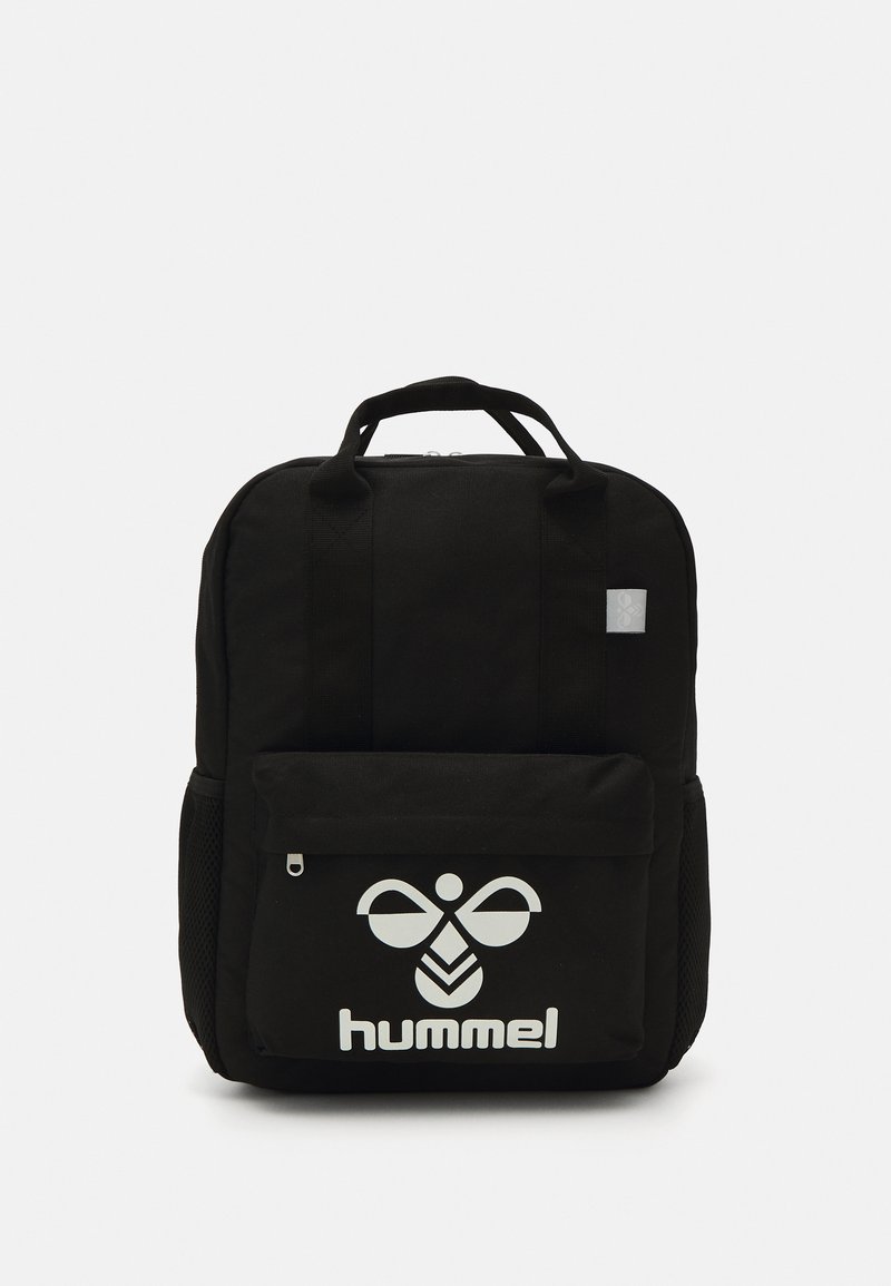 Zwarte stoffen rugzak met twee handgrepen, een voorzak met ritssluiting, gaas zijvakken en een groot wit logo aan de voorkant. Eenvoudig rechthoekig ontwerp.