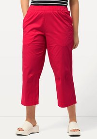 Röda cropped byxor i lätt material med elastisk midja och sidofickor. Slät textur med en ren nederkant.