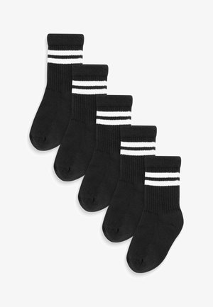 Chaussettes noires avec des rayures blanches en haut, présentant une texture côtelée. Cinq paires soigneusement disposées pour l'exposition.