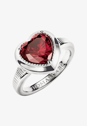 Silberner Ring mit großem facettiertem, herzförmigem rotem Edelstein, auf dem Ringband mit "THOMAS SABO" graviert.