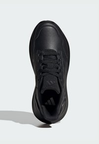 Scarpa sportiva nera con tomaia in pelle texturizzata, lacci piatti, colletto imbottito e suola in gomma liscia con un sottile dettaglio del logo.