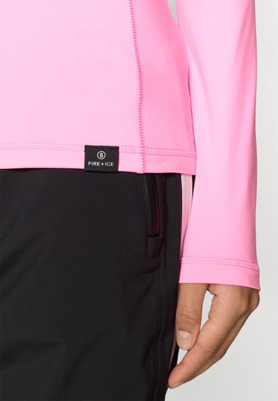 Ροζ μπλουζάκι με μακριά μανίκια, φτιαγμένο από ελαστικό υλικό, με επίπεδες ραφές και μαύρη ετικέτα με την ένδειξη "FIRE+ICE", συνδυασμένο με μαύρο παντελόνι.