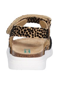 Schwarze und braune gepunktete Sandalen mit Korkfußbett, kontrastierender weißer Sohle und verstellbarem Riemen. Die Rückansicht zeigt das offene Fersen-Design.