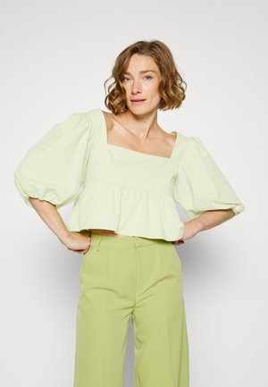 Top crop verde menta com decote quadrado, mangas bufantes e bainha com babados, combinado com calças largas verde claro feitas de tecido suave.