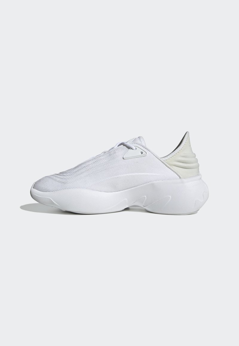 Białe nowoczesne sportowe sneakersy z teksturowaną plecioną cholewką, rzeźbioną żebrowaną podeszwą środkową i wyściełanym kołnierzem pięty, umieszczone na jasnoszarym tle.