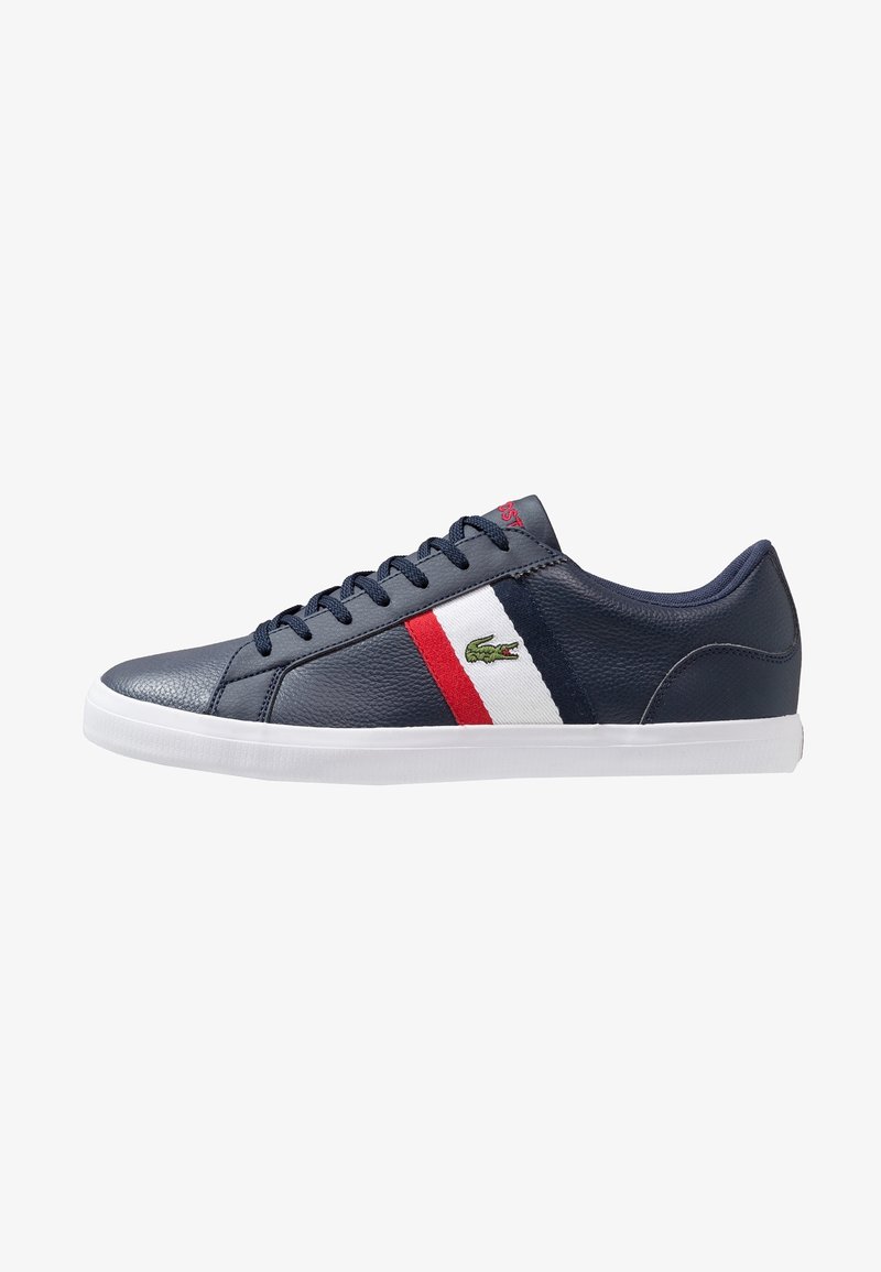 Navy leather sneakers featuring a red and white stripe, with a green logo on the side and a white rubber sole.