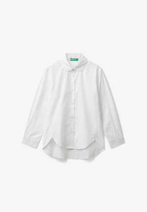 Camicia bianca a maniche lunghe con bottoni, colletto e orlo asimmetrico, adagiata su uno sfondo bianco.