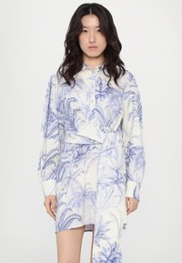 Rochie camasă albastră și albă cu imprimeu de frunze de palmier, mâneci lungi, închidere cu nasturi și detaliu de talie legat. Fabricată dintr-un material ușor.