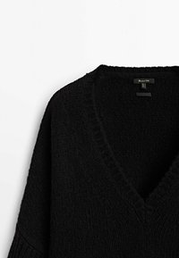 Black knitted sweater featuring a v-neckline, loose fit, and subtle ribbed detailing along the neckline and cuffs. Soft texture.