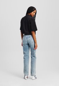Camicetta nera a maniche corte e cropped abbinata a jeans azzurri a vita alta e sandali bianchi con tacco. Design semplice con dettagli minimi.