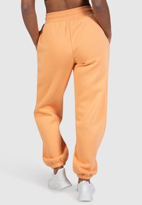 Peachfarvede sweatpants med en elastisk talje og cuffs, lavet af blødt stof, med to sidelommer og en afslappet pasform.
