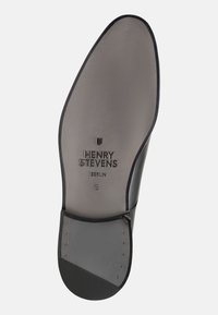 Semelle de chaussure en cuir noir avec logo embossé "HENRY STEVENS BERLIN" et taille 8. Fini texturé, forme arrondie et petites clous en métal.