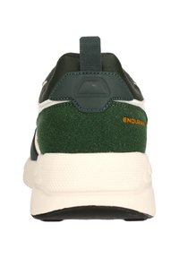 Grön sportskor med mocka- och meshmaterial. Har en vit mellansula, strukturerad svart yttersula och "ENDURANCE" i orange på hälen.