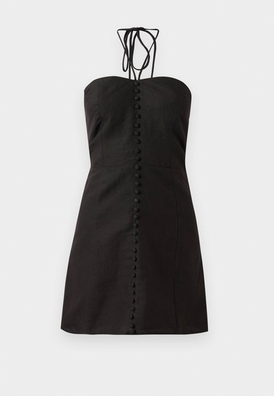 Musta, olkaimeton mekko, joka on valmistettu teksturoidusta kankaasta ja jossa on suora leikkaus. Siinä on edessä nappisuljenta pyöreillä napeilla ja säädettävät siteet kaulassa.