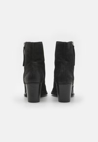 Botine negre din suede, cu vârf rotund, toc mic și un detaliu cu fermoar pe lateral. Textură netedă și design elegant.