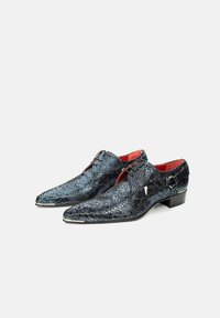 Zwarte en blauwe slangenleer schoenen met puntige neuzen, vetersluiting, rode binnenkant en een kleine hak. Kenmerkend zijn de metallic accenten en het gestructureerde oppervlak.
