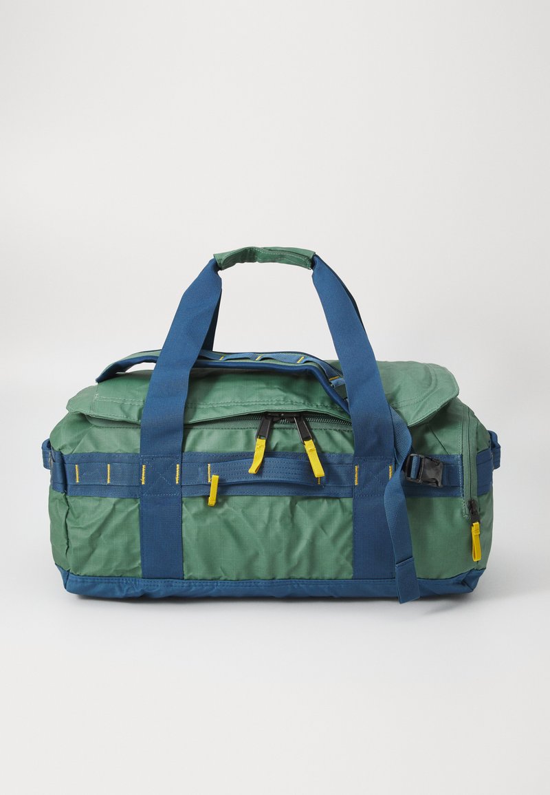 Green and blue duffel bag made of durable fabric, featuring dual handles, yellow accents, and a zippered top closure for easy access.