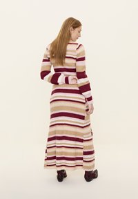 Rochie maxi tricotată în modele rayate de burgund, roz și bej. Mâneci lungi cu mansete ribbate, fante laterale și material texturat.