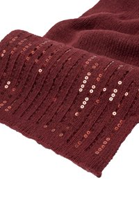 Tuvumā redzams salocīts bordo adījuma audums ar vertikālām rindām mirdzošiem apaļiem spīguļiem, kas rotā auduma tekstūru.