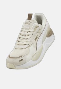 Baskets beiges en matériaux mixtes avec mesh et daim, bout arrondi, accents cousus, et semelle intermédiaire blanche. Logo Puma sur la languette.