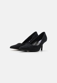 Schwarze Wildleder-Pumps mit hohen Absätzen, einer spitzen Zehenpartie und einem schlanken Absatz, die eine glatte Textur und ein minimalistisches Design aufweisen.