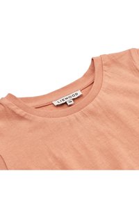 T-shirt w kolorze brzoskwiniowym z okrągłym dekoltem, miękka faktura i metka z nazwą marki "LIEWOOD" oraz rozmiarem 110.