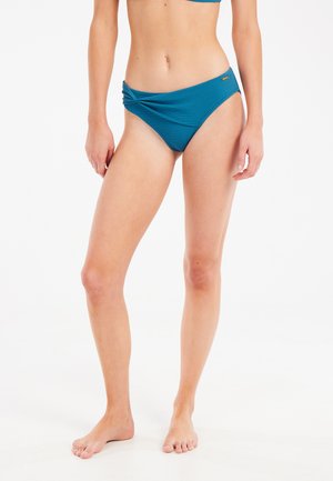 Parte inferiore di bikini color turchese con tessuto testurizzato, caratterizzata da un dettaglio annodato sul davanti. Design a vita media con copertura moderata.