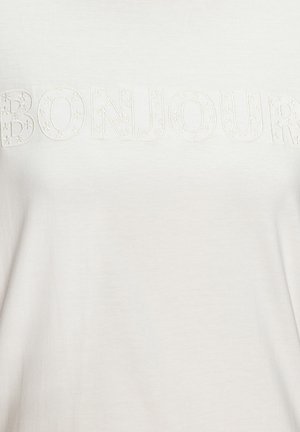 Bijela tkanina s uzdignutim izvezenim slovima koja tvore riječ "BONJOUR", ukrašena malim cvjetnim uzorcima.